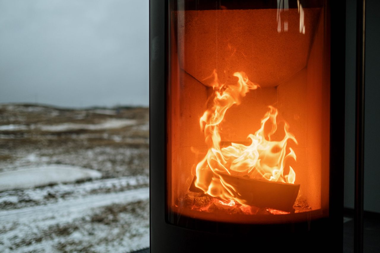 Home Indoor fireplace with burning flame creating warmth against snowy winter outdoors.